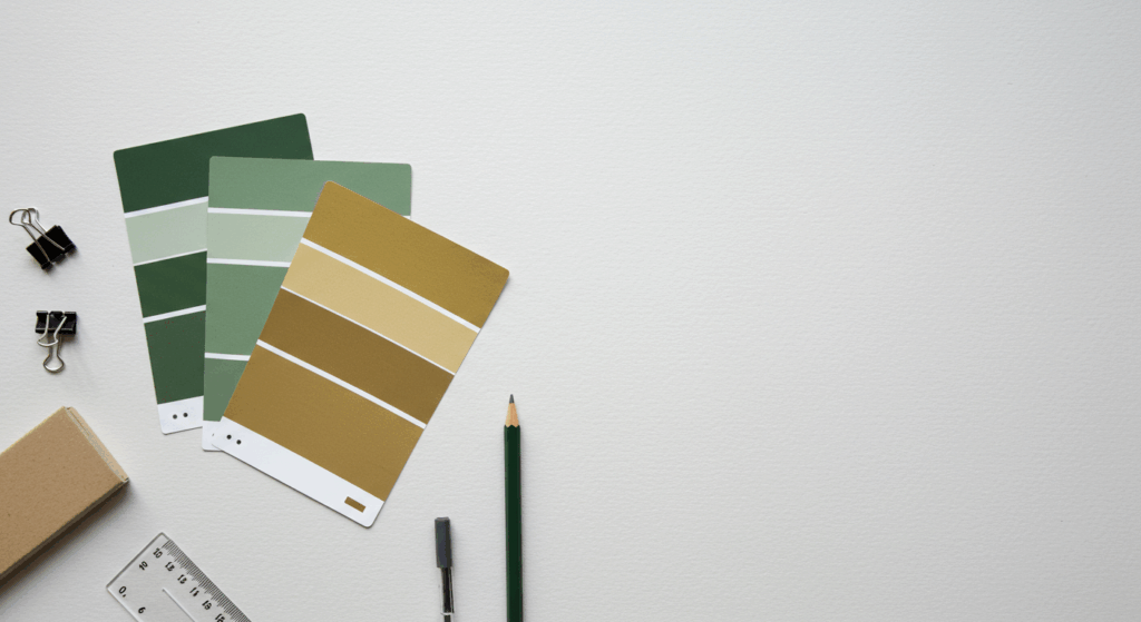 A flat lay of professional design tools, including green and gold colour swatches, symbolizing the strategic brand identity and colour palette selection process.
