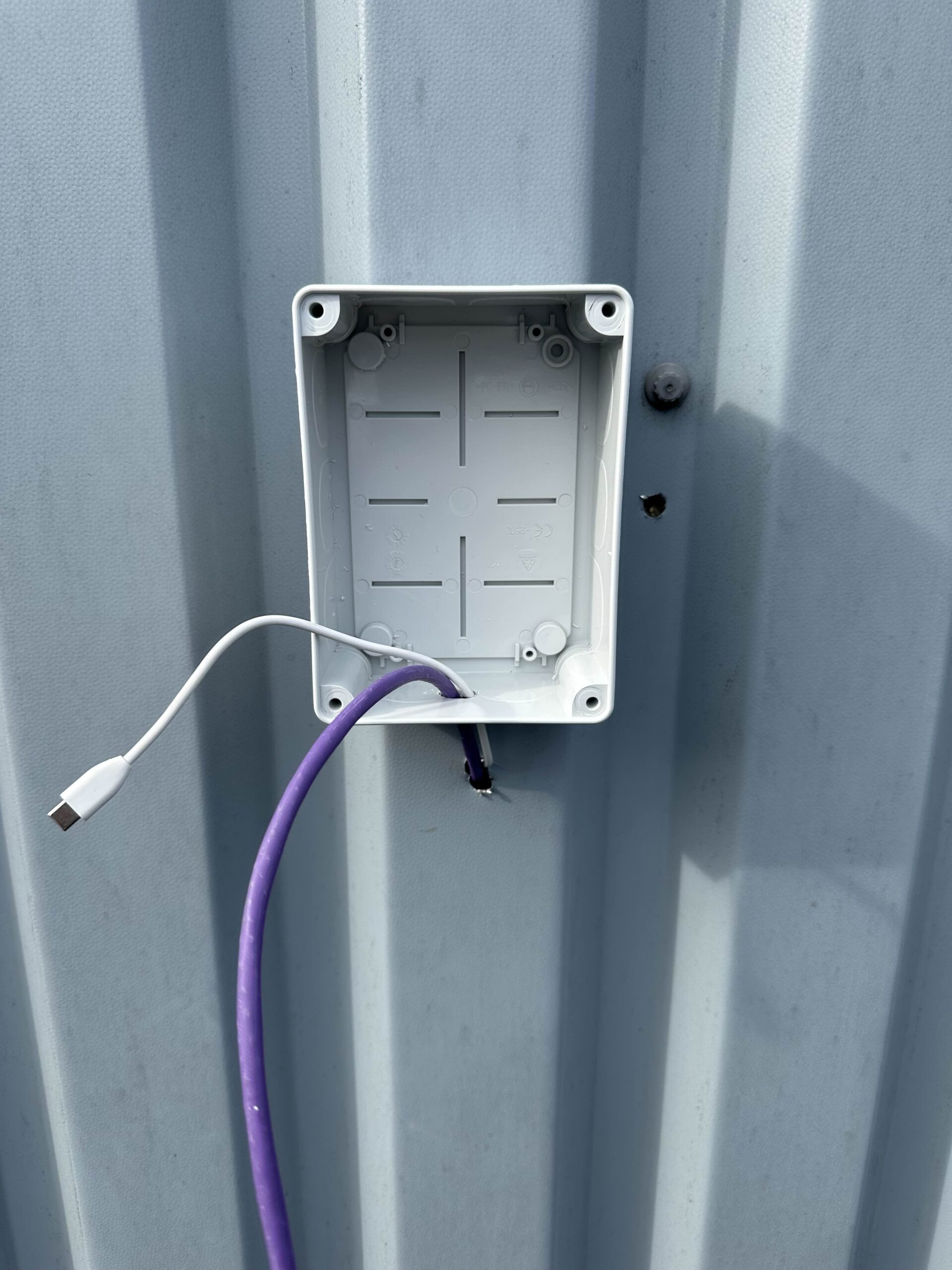 The network and power cables being professionally installed into a weatherproof junction box, a vital part of a reliable Wi-Fi installation for metal buildings.